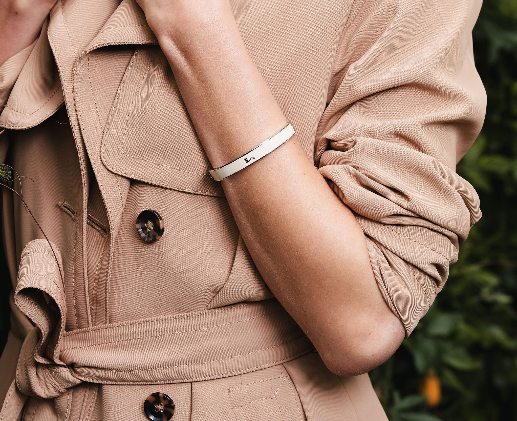 Model wearing the Forever Coo sterling silver motherhood bracelet styled with a classic beige mac coat.