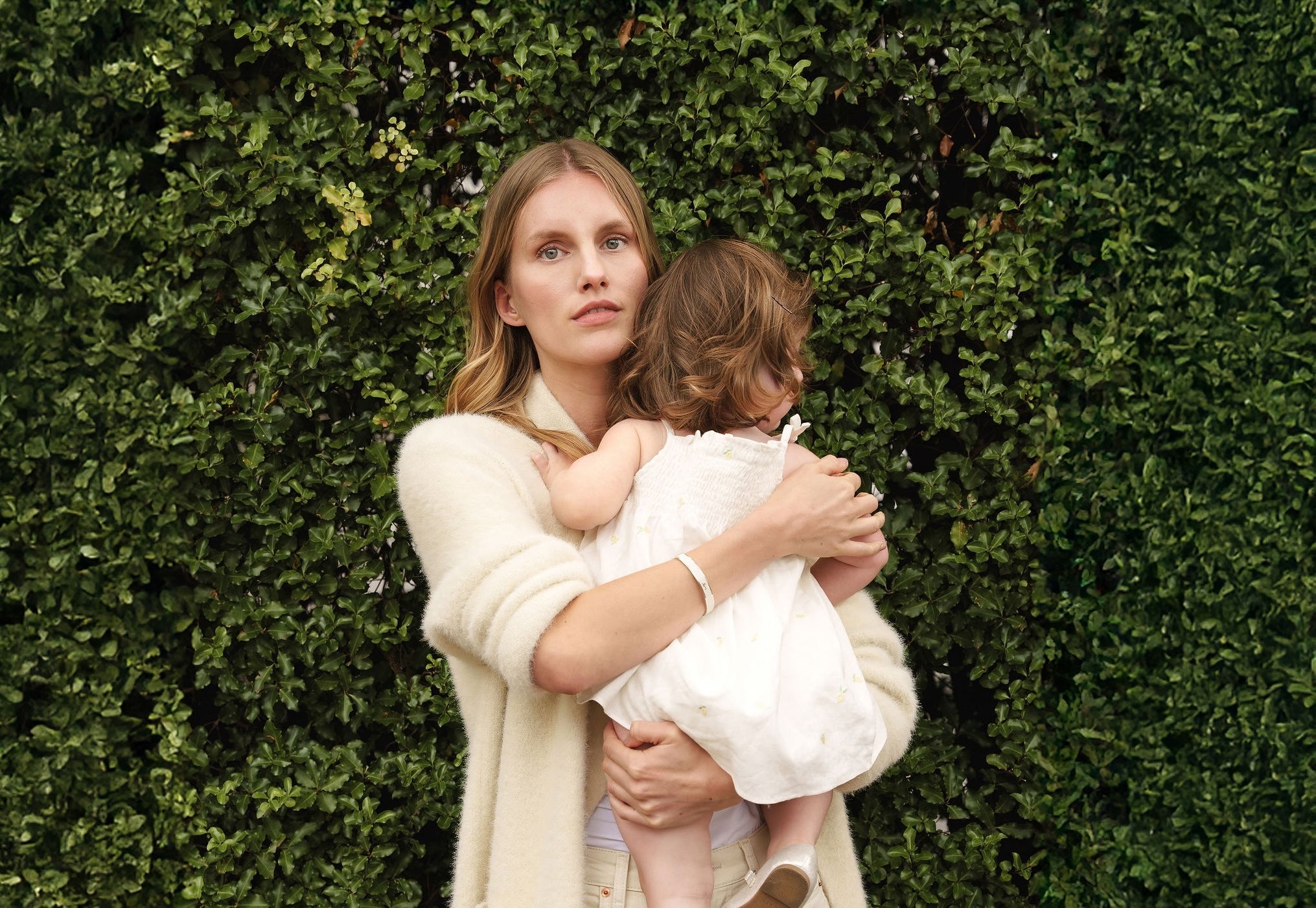 Mother holding child in garden whilst wearing her Vivi Coo Forever Coo bracelet. 